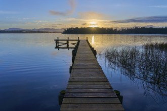 Wooden jetty reaches into the lake as the sunrise illuminates the dawn on Lake Mahinapua, Ruatapu,