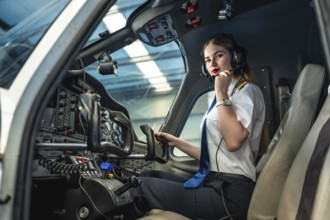 Confident female pilot preparing for takeoff, sitting in the cockpit of a small airplane, adjusting