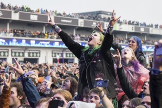 Festival visitors on shoulders with a French fries fork shaped like a hand at the Rock am Ring