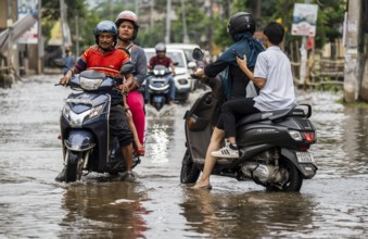 Commuters passing through a waterlogged street following heavy rainfall in Guwahati, India, on 1