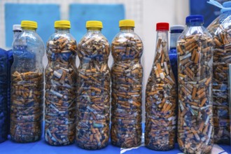 Plastic bottles filled with cigarette butts collected during a beach cleanup highlight