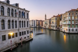 View of the Grand Canal with gondoliers at sunset, picturesque evening mood with illuminated