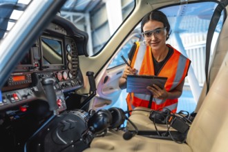 Female aircraft maintenance engineer taking notes while inspecting the cockpit panel of a small