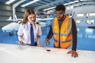 Aircraft maintenance engineer shows a fuel sample to a pilot during a pre flight check in a hangar