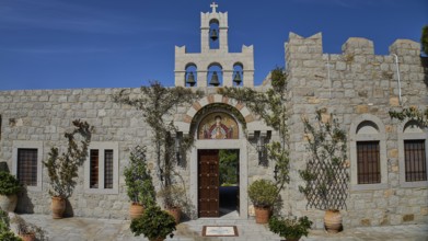Church façade with bell tower and religious icon, surrounded by plants, woman's monastery,
