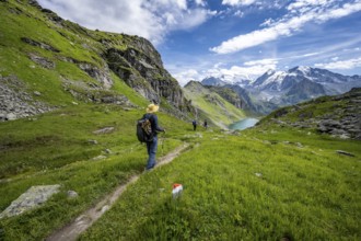 Mountaineer on hiking trail in mountain landscape, descent from Col du Louvie, view of Lac du