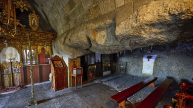 Church interior with icons and wooden benches set into a stone wall, Cave of St John, Grotto of