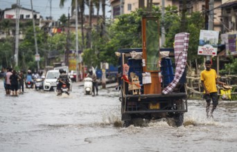 Commuters passing through a waterlogged street following heavy rainfall in Guwahati, India, on 1
