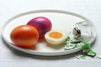 Easter eggs and salt shaker on plate, partially peeled