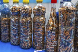Plastic bottles filled with used cigarette butts highlight the environmental impact of smoking and