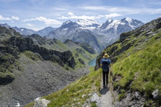 Mountaineer on hiking trail in mountain landscape, descent at Col du Louvie, view of the summit of