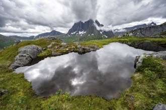 Small lake in mountain landscape, hike to Mount Barden, reflection with mountain peak Breidtind,