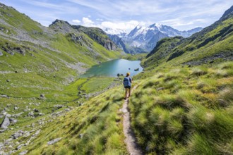 Mountaineer on hiking trail in picturesque mountain landscape, view of mountain lake Lac du Louvie