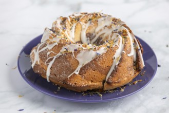 Marble bundt cake, cake with icing and edible flowers on a blue plate, light background