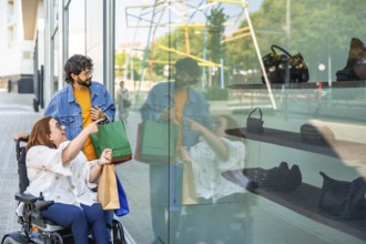 Happy friends doing shopping and looking at a shop window, a disabled woman on a wheelchair is