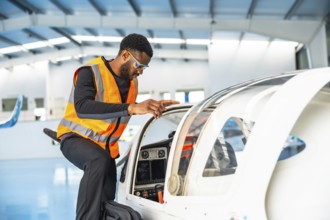 Aircraft maintenance engineer wearing safety glasses and a high visibility vest is inspecting the