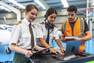 Aviation maintenance team working together, using a laptop and checklists for pre flight inspection