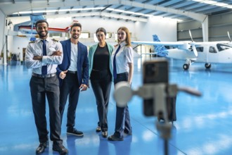 Pilots and a manager recording a video on a smartphone mounted on a tripod inside an aircraft