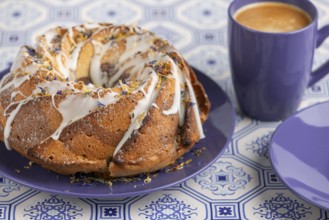Marble bundt cake, cake with icing and edible flowers on a blue plate with coffee