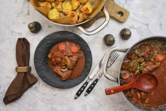 Tender beef stew filled with vegetables is plated on a dark dish, accompanied by a side of seasoned