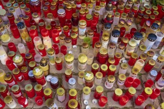 Many candles in different colours stand close together, creating a festive and contemplative