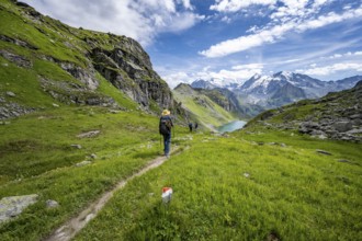 Mountaineer on hiking trail in mountain landscape, descent from Col du Louvie, view of Lac du