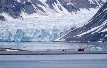 A sailboat in front of a glacier in a cold and calm arctic landscape, Magdalenenfjord with