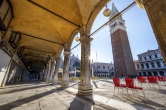 Chairs and tables of cafes, arcades at St Mark's Square in the morning light, St Mark's Basilica