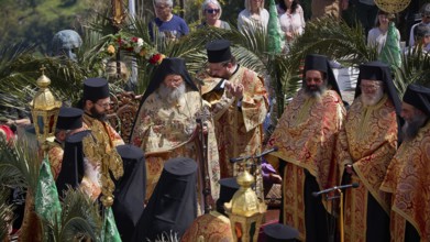 Orthodox priests in splendid robes hold a solemn ceremony with golden elements and palms, Orthodox