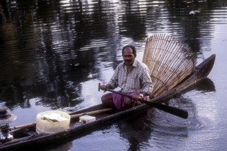 Fisherman with bamboo fishing basket fishing in the backwater of Kuttanad, Kerala, South India,