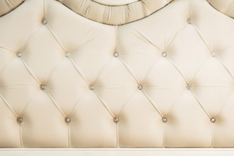 Beige soft textile background with symmetrical buttons on the corners of diamonds. Soft and