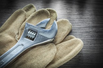 Adjustable spanner Protective leather gloves on wooden board