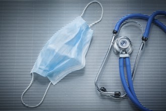 Disposable stethoscope with face mask on striped background