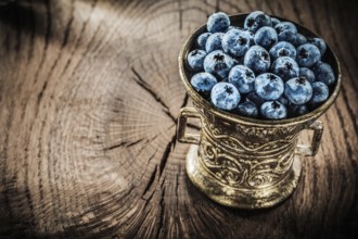 Blueberries in vintage metal bowl on grunge board