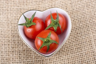 Red ripe cherry tomatos tomatos in heart shaped bowl