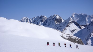 group of backcountry skiers crossing a glacier on their way to a high summit in the Alps of