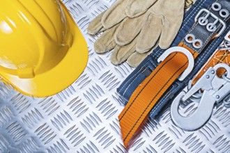 Yellow helmet, safety harness and gloves on corrugated metal plate