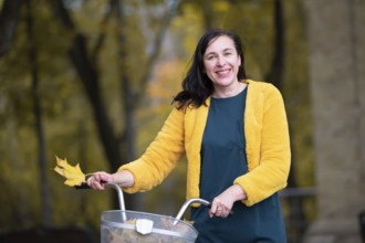 Happy middle-aged woman with bike in autumn park