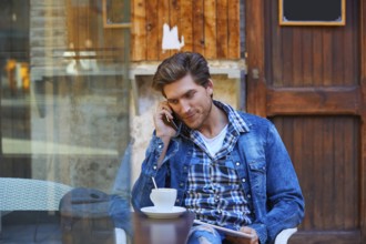 Young man with smartphone in an cafe outdoor sitting