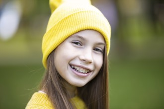 Beautiful teenage girl wearing braces smiling happily dressed in bright yellow clothes outdoors.