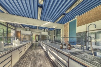 An abandoned laboratory room with long benches and glass containers under daylight, Institute of