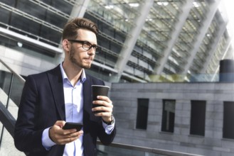 Handsome successful businessman in elegant suit outdoors stand at street in the city with coffee