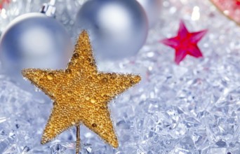 Christmas golden star symbol with silver baubles and red ribbon on ice