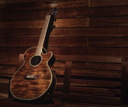 Acoustic brown guitar in a wooden stripes wooden wall monochromatic