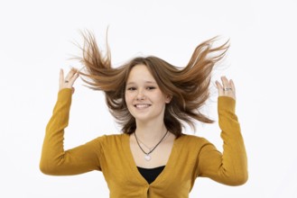 A cheerful girl enjoys her vibrant hair, complemented beautifully by her bright yellow sweater that