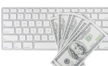 US hundred dollar bills with white computer keyboard isolated on white background