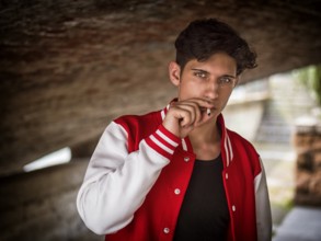 Handsome stylish young man smoking outside in urban setting, looking at camera