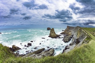 Powerful surf waves with a foam crest. Dramatic stormy sky. Cantabria Beaches, Portio Beach. Windy