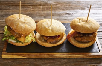 Burger in a row on a slate board and wood table
