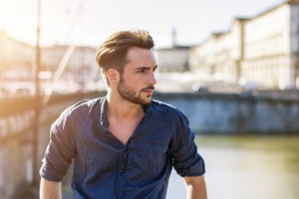 One handsome young man in urban setting in European city, Turin in Italy by the river Po